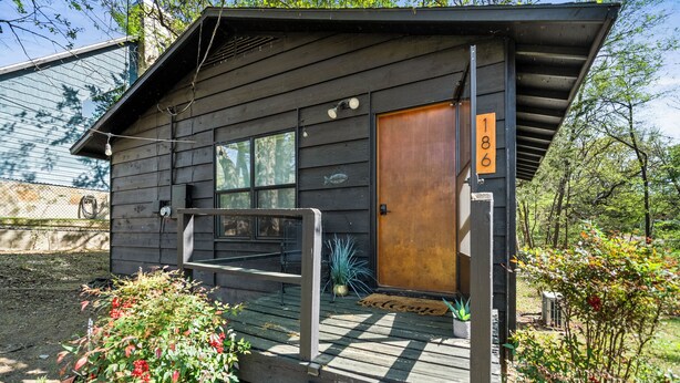 Une cabane en bois avec une porte en bois, une plaque de numéro et un porche avec des marches.