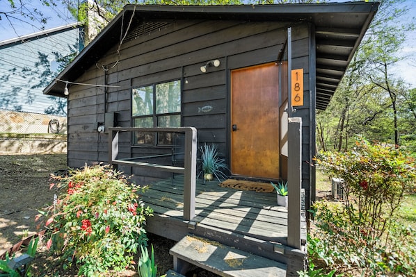 A wooden cabin with a wooden door, a number plaque, and a porch with steps.
