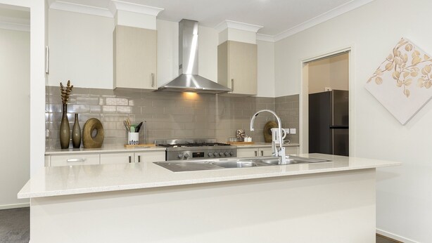 A modern kitchen with a central island, stainless steel appliances, and a decorative wall piece. - Comfort and Space in Lara's Family Friendly Home (Geelong)