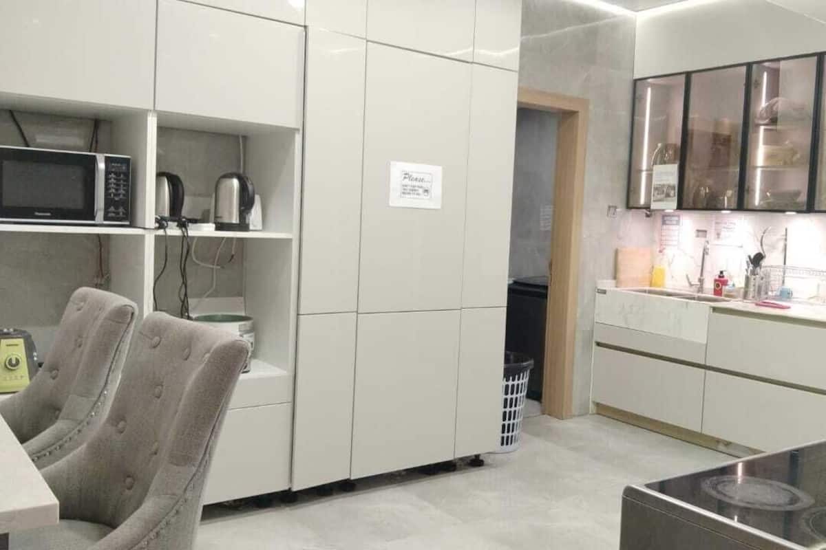Une cuisine moderne avec des meubles blancs, un four à micro-ondes, une bouilloire et une cuisinière en acier inoxydable.