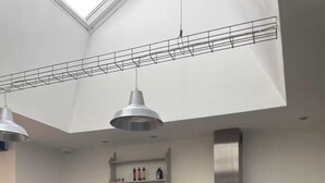 Une cuisine moderne dotée d’une lucarne, d’un réfrigérateur noir, d’une machine à café et d’un vase en verre illuminé.