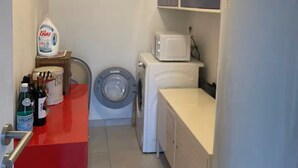 Une petite buanderie équipée d’un lave-linge, d’un four à micro-ondes et d’un évier.