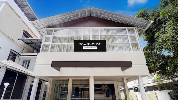 A modern townhouse with a sign indicating it is company-serviced, large windows, and a covered entrance. - Deluxe Keyen Arcade (Kanayannur)