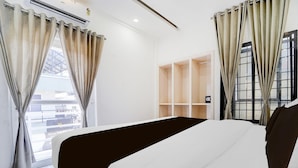 A hotel room with a bed, curtains, a wardrobe, and a window with a view. - Deluxe Keyen Arcade (Kanayannur)