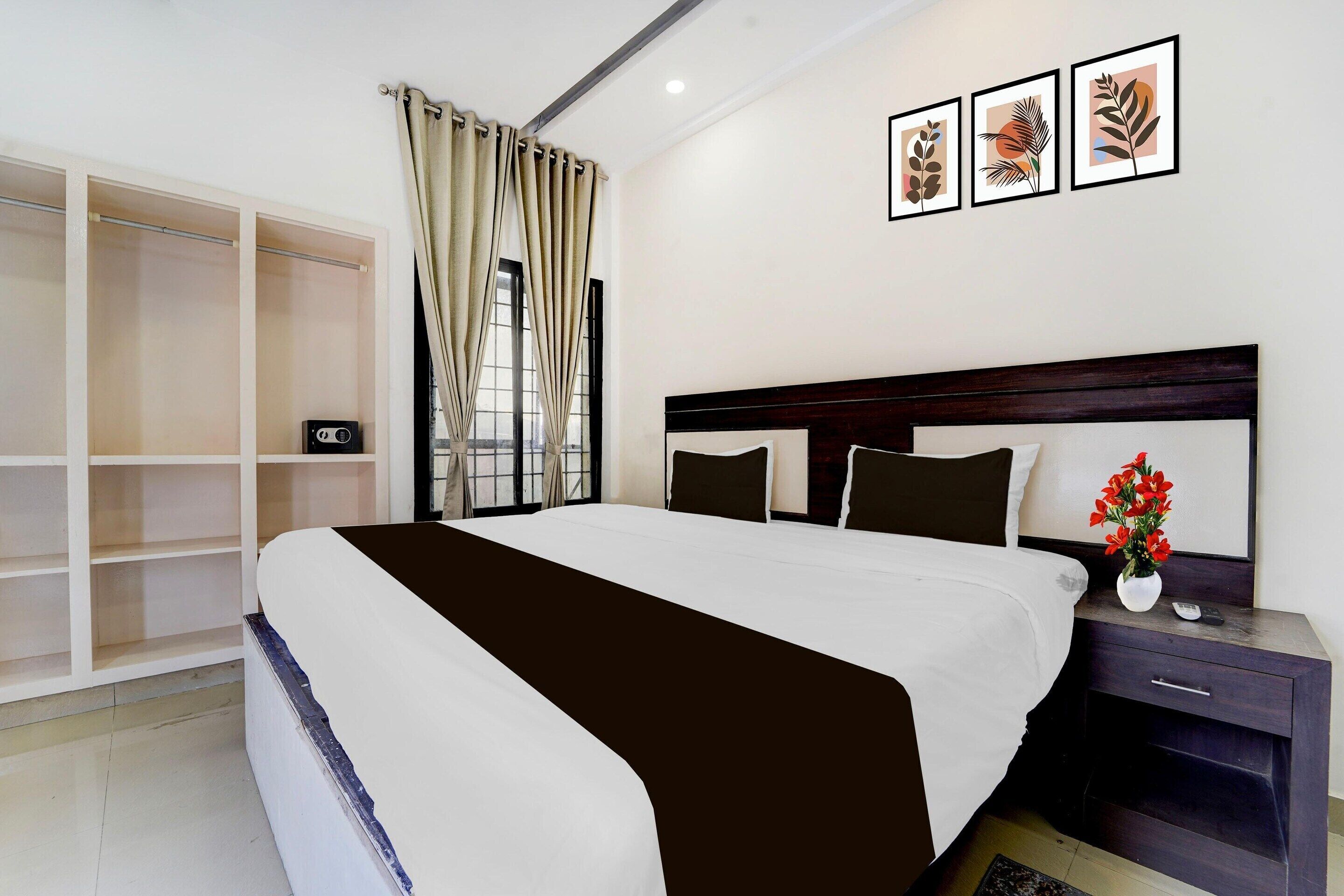 A bedroom with a large bed, a nightstand, a wardrobe, and a window with curtains.