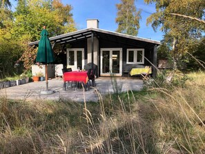 Ein modernes Haus mit Terrasse, einem Tisch mit Stühlen und einem grünen Sonnenschirm.