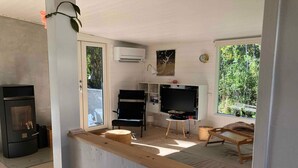 A room with a fireplace, a television, a wooden bench, and a view of greenery outside. - 4 Star Holiday Home in Nykobing Sj (Nykobing Sjaelland)