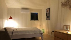 A bedroom with a bed, a desk, a chair, a TV, and an air conditioning unit. - 4 Star Holiday Home in Nykobing Sj (Nykobing Sjaelland)