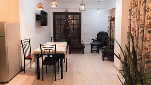 A dining area with a table, chairs, and hanging light fixtures. - Mavick Gardens Apartment for rent per day (Anuradhapura)