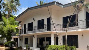 A two-story house with a balcony, a covered porch, and a garden area. - Mavick Gardens Apartment for rent per day (Anuradhapura)