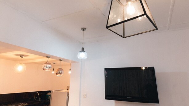 A modern kitchen with pendant lights, a flat-screen TV, and a refrigerator. - Mavick Gardens Apartment for rent per day (Anuradhapura)