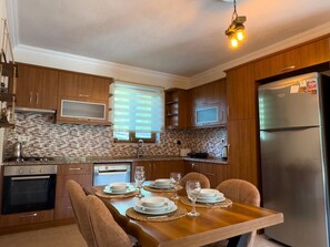 A modern kitchen with wooden cabinets, a built-in oven, a microwave, and a stainless steel refrigerator. - Villa Casa de Piedra (Fethiye)