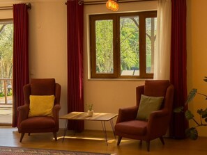 A room with two armchairs, a small table, and a window with a view of trees. - Villa Casa de Piedra (Fethiye)