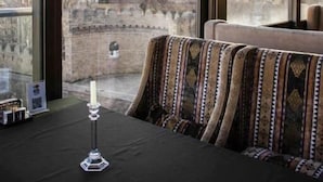 A room with large windows, a black table with a candle, and patterned cushions. - Moon Light Hotel (Baku)