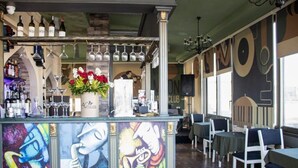 A bar area with a counter, wine glasses, and a flower arrangement. There are tables and chairs in the dining area. - Moon Light Hotel (Baku)