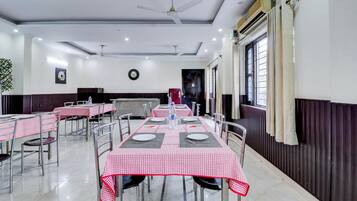 Comedor con mesas dispuestas para cuatro, ventiladores de techo y aire acondicionado.