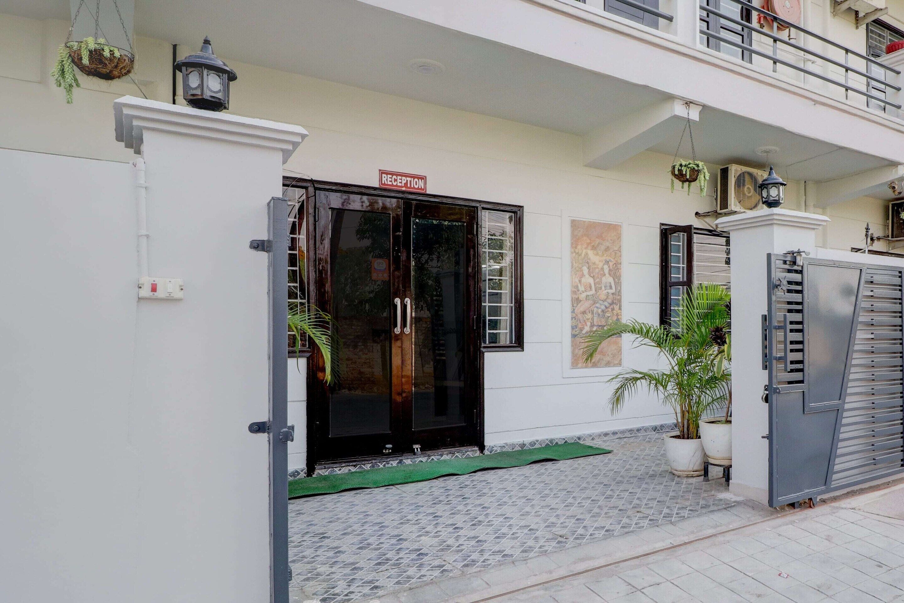 A reception area with a closed door, a sign above it, and a potted plant beside the door.
