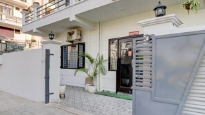 A gated entrance to a building with a reception sign, a potted plant, and a tiled entrance area. - Deluxe Benison Guest House (Dehradun)