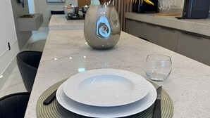 Eine Küchenarbeitsplatte mit einem weißen Teller, einem Glas und einem Messer auf einer gewebten Tischmatte.