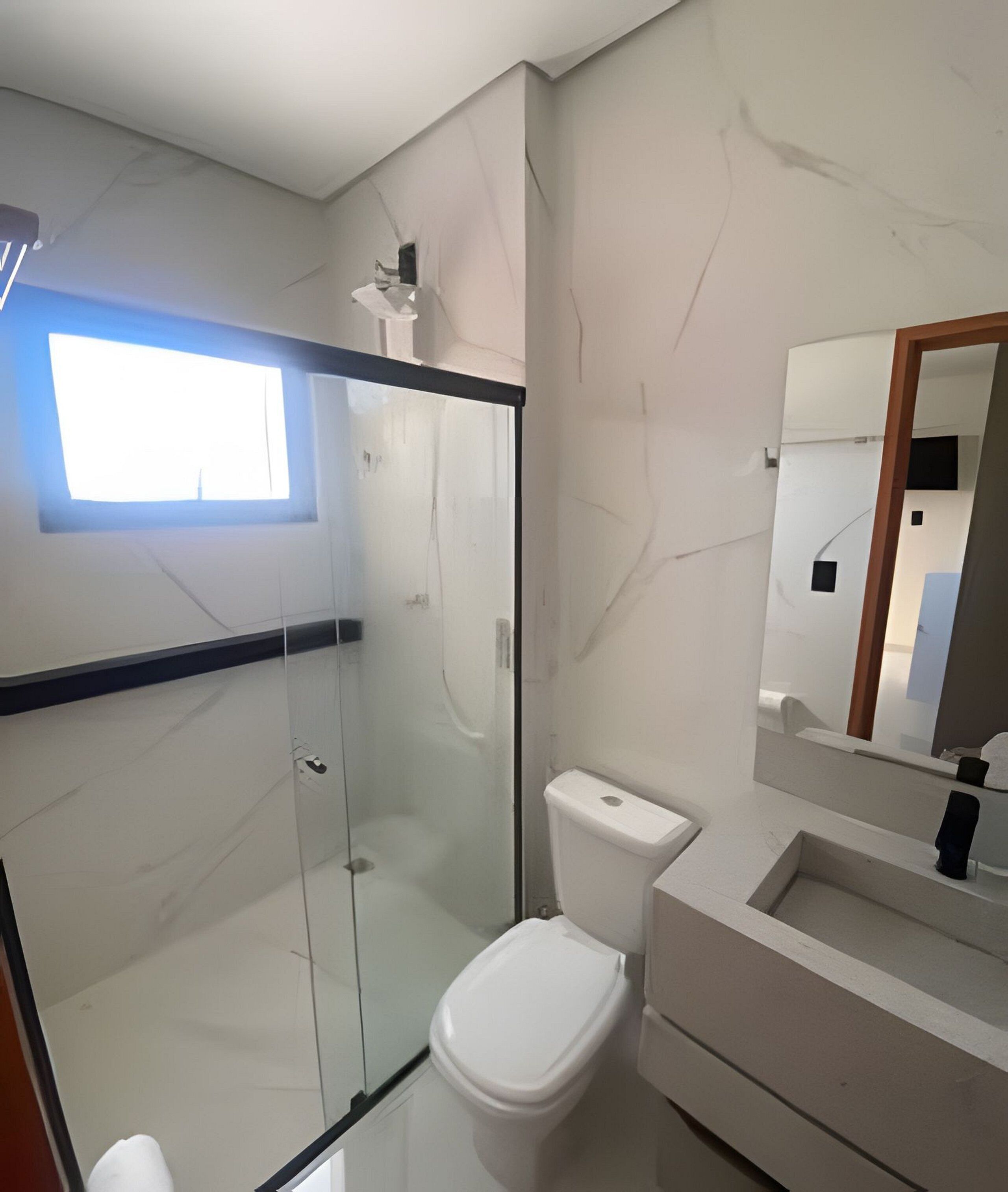 A modern bathroom with a glass-enclosed shower, a toilet, and a sink with a mirror above it.