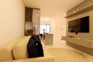 A modern living room with a sofa, a TV mounted on the wall, and a decorative partition.