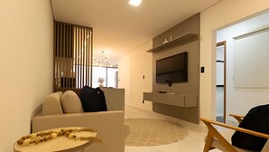 Ein modernes Wohnzimmer mit einer Couch, einem kleinen Tisch, einem Fernseher und einer Holzwand.