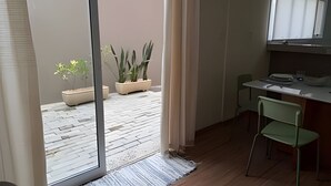 Habitación con puerta de vidrio corredera que da a un espacio exterior con plantas en macetas.