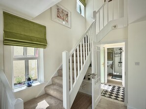 A staircase with white railings leading to a room with a window, a door to a bathroom, and a checkered floor. - Cottage 493 - Clifden - sleeps 5 guests  in 3 bedrooms (Clifden)