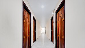 A long, narrow hallway with wooden doors on both sides and a tiled floor.