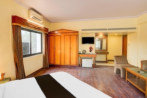 Une chambre d’hôtel comprenant un lit, un bureau, une chaise, une télévision et une armoire.