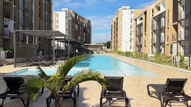 A modern hotel with a swimming pool, sun loungers, and a well-maintained lawn. - Apartment in Bávaro Punta Cana | Swimming Pool | Near the Beach (Punta Cana)