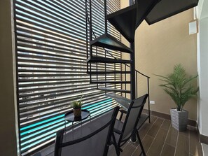 Ein Balkon mit Tisch, Stühlen und einem Blumentopf.