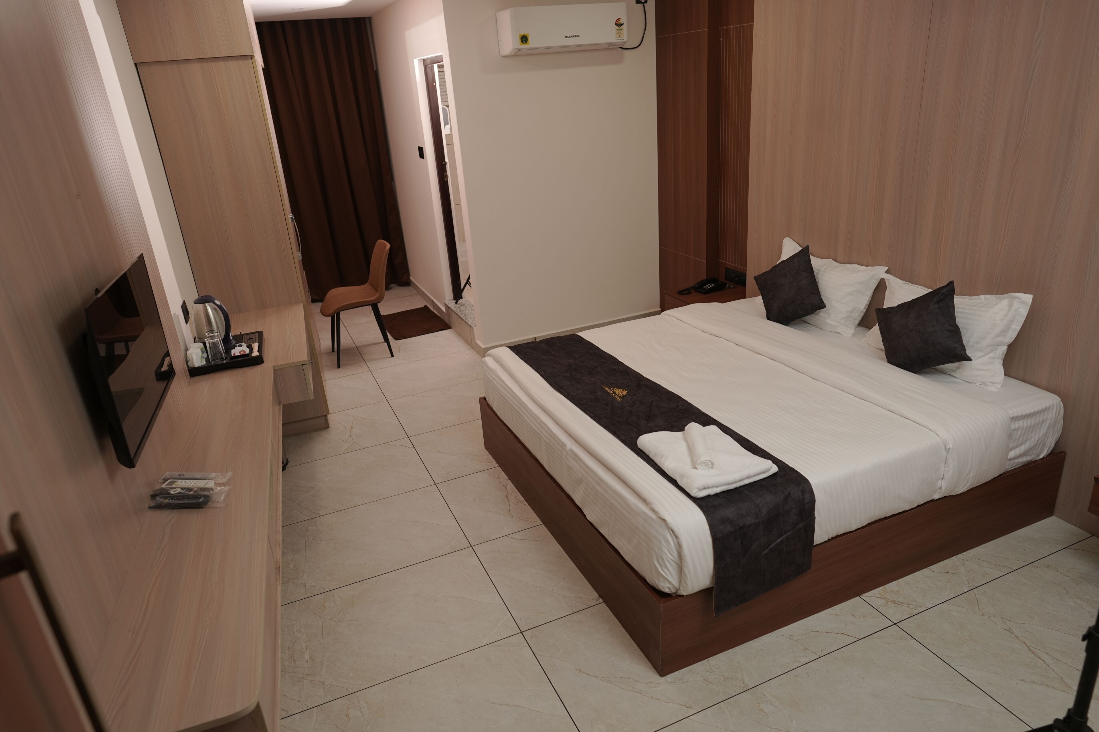 Una habitación de hotel con cama, televisor, escritorio y silla.
