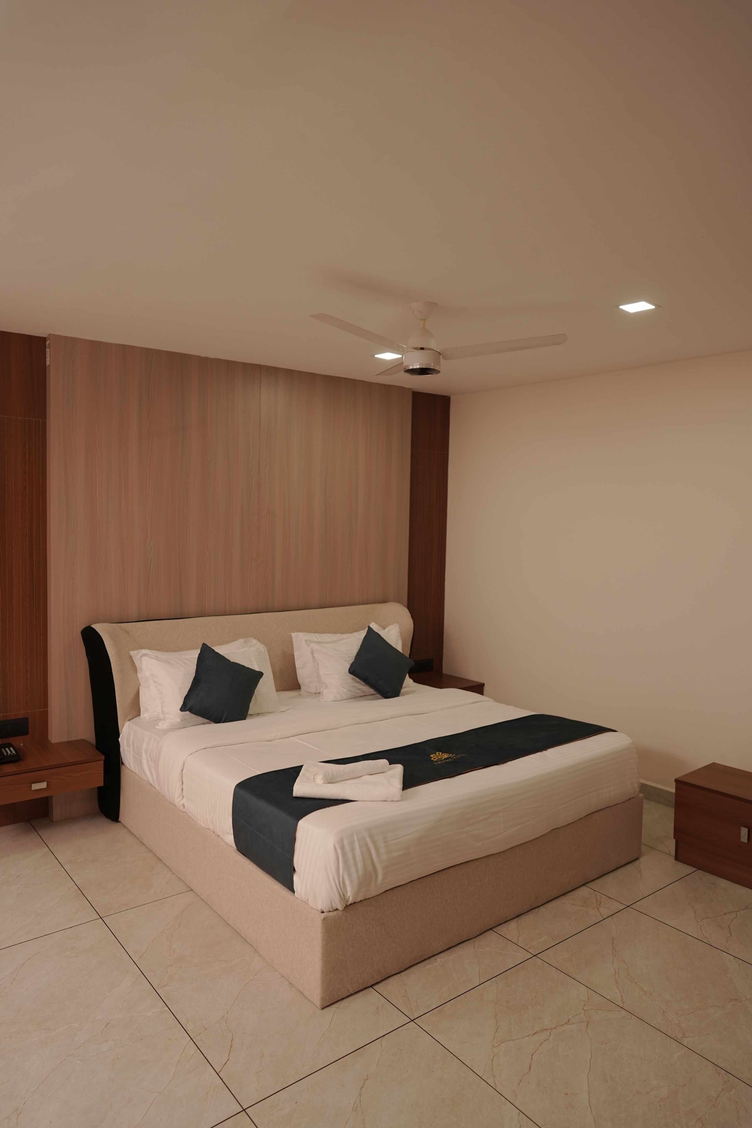 Une chambre à coucher moderne avec un grand lit, un ventilateur de plafond et une table de chevet.