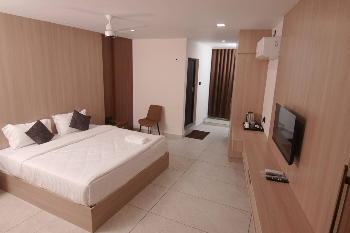 A modern hotel room with a large bed, a TV, and a seating area.