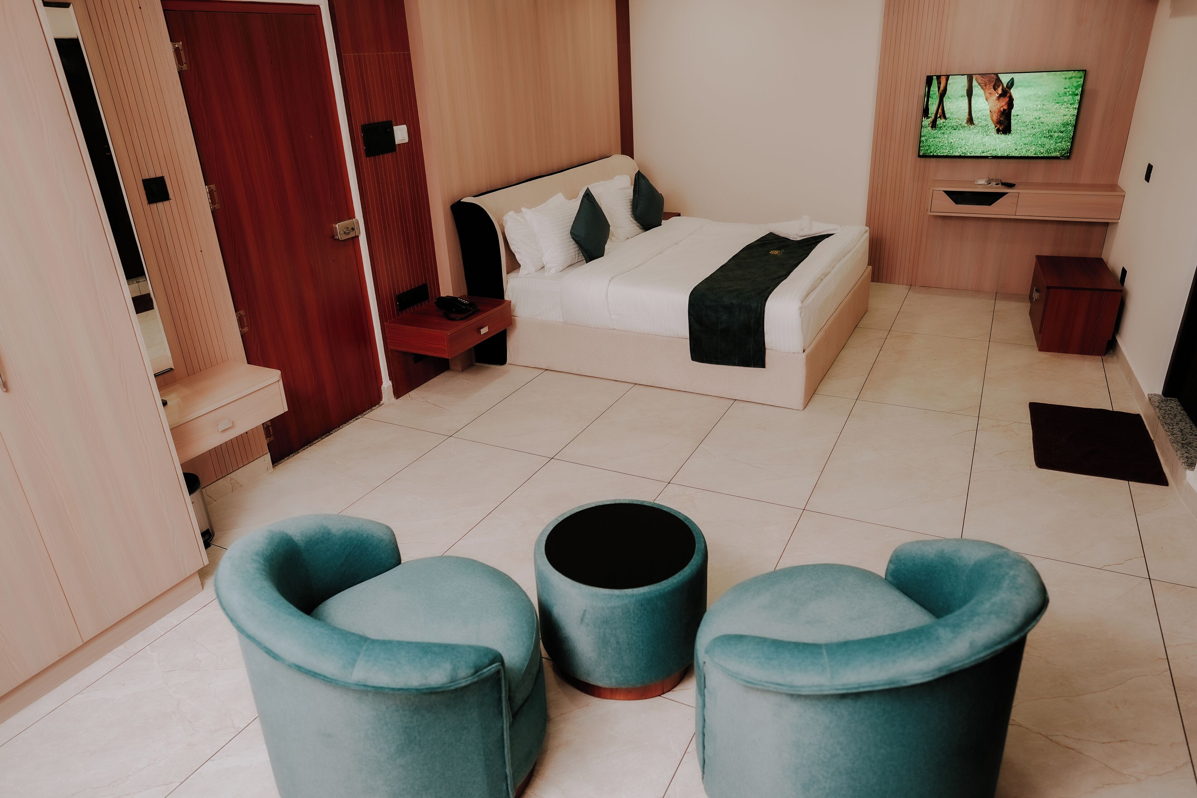 Une chambre d’hôtel moderne avec un lit, une télévision et deux chaises bleues.