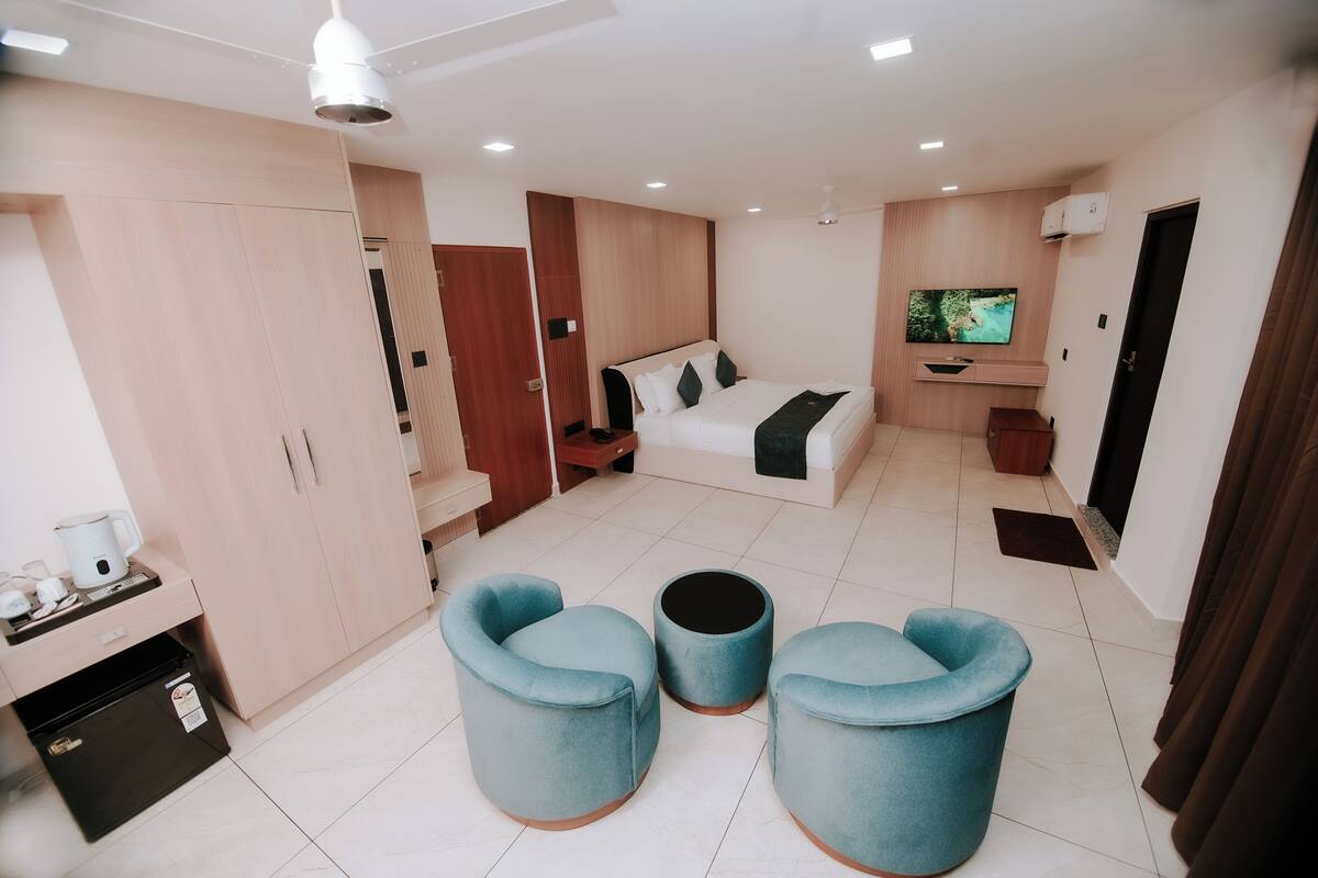 A modern hotel room with a bed, TV, and seating area.