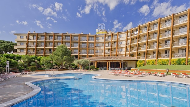 A hotel with a large swimming pool, multiple balconies, and a clear blue sky. - Studio in Tossa de Mar Near Beach & City Center (Tossa de Mar)