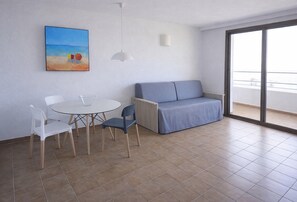 Una habitació amb taula de dinar, cadires, sofà i una finestra gran que ofereix una vista.