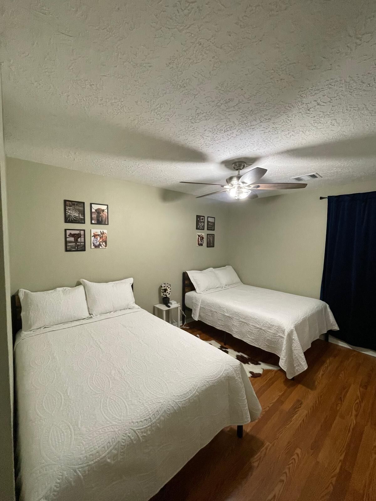 Ein Zimmer mit zwei Betten, einem Deckenventilator und Bildern an der Wand.
