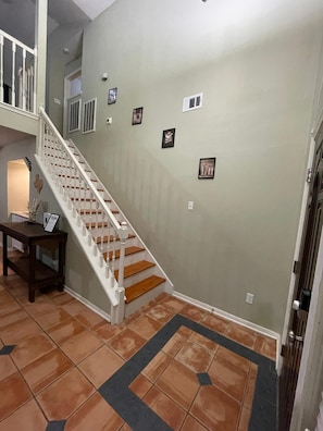 Una escalera con barandillas blancas y escalones de madera que sube a un nivel superior.
