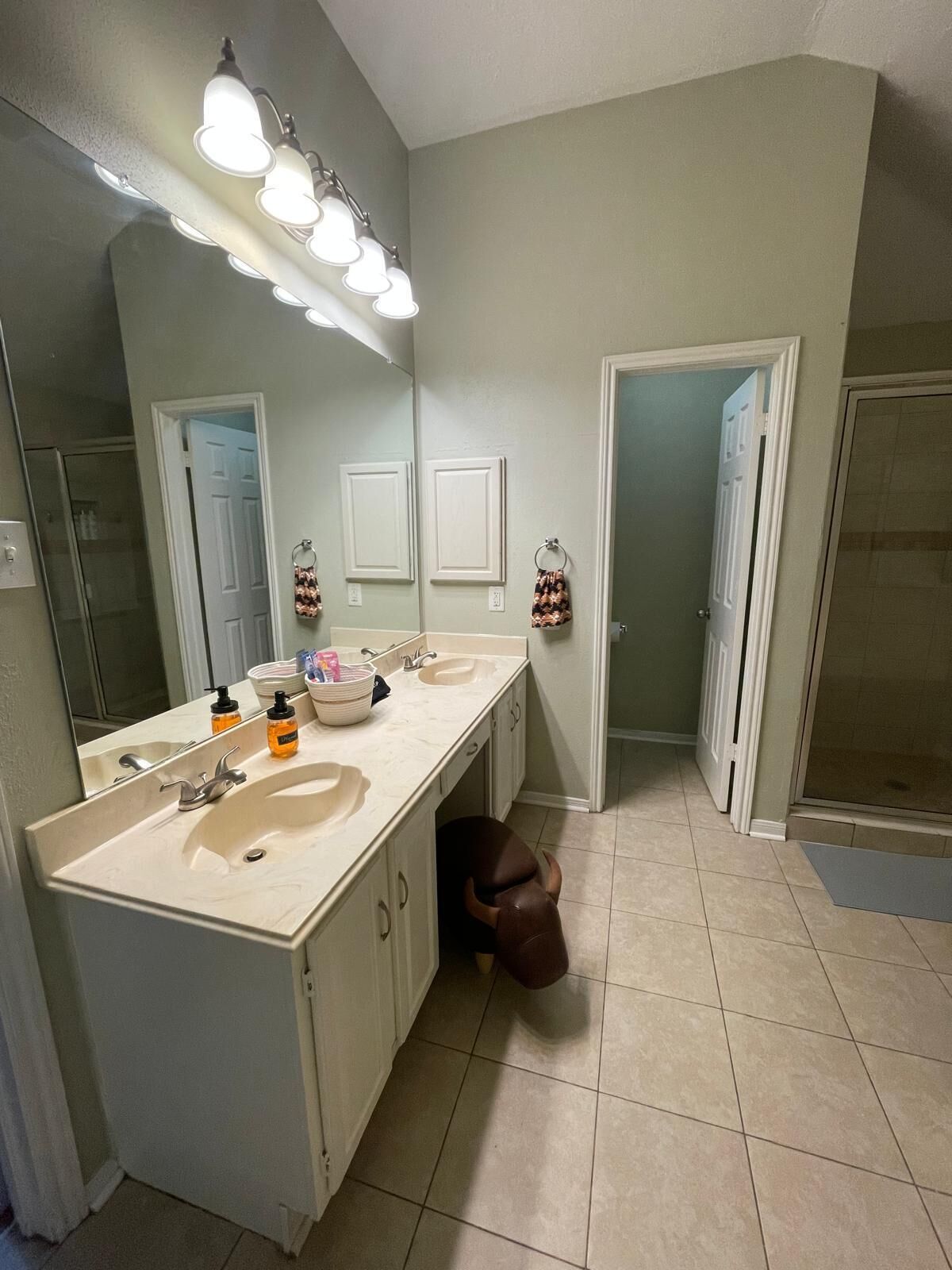 A bathroom with two sinks, a large mirror, and a shower area.