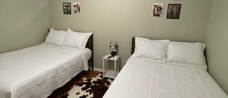A room with two beds, a ceiling fan, and wall-mounted pictures.