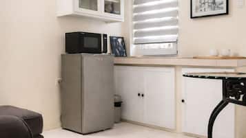 Una cocina compacta con refrigerador, microondas y armarios.