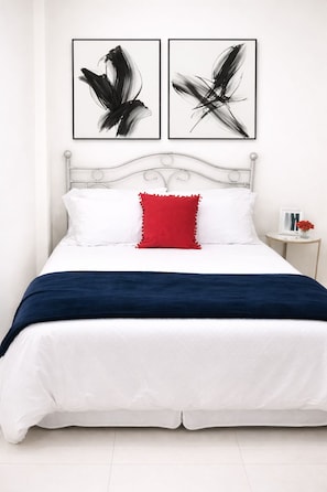 A bed with white bedding, a red pillow, and two abstract art pieces above it. - Cozy 1-bedroom apartment in amazing Tunapuna/Piarco Regional Corporation with AC (Tunapuna/Piarco Regional Corporation)
