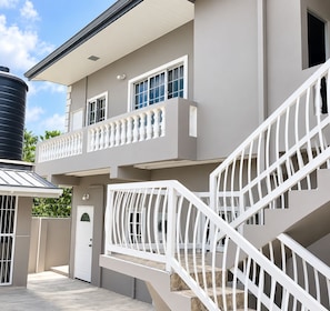 A two-story building with a balcony, a staircase, and a door. - Cozy 1-bedroom apartment in amazing Tunapuna/Piarco Regional Corporation with AC (Tunapuna/Piarco Regional Corporation)