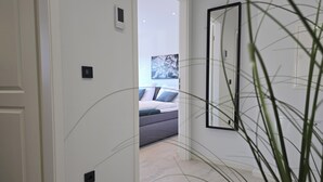 A hallway with a door leading to a bedroom with a bed and a painting on the wall. - Modern Apartment with Balcony near Airport (Siegburg)