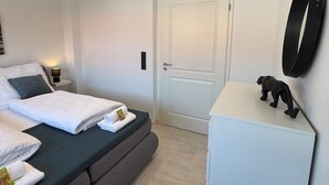 A modern hotel room with a bed, bedside table, and a small cabinet. - Modern Apartment with Balcony near Airport (Siegburg)