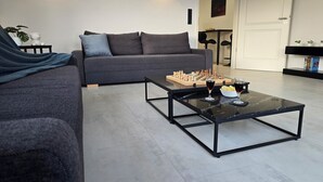 A modern living room with a sofa, a coffee table with chess, and a door in the background. - Modern Apartment with Balcony near Airport (Siegburg)