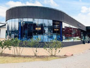 A modern building with a curved facade, large glass windows, and a sign reading 'GLASBÄREN.' - 6 Person Holiday Home in Kosta (Kosta)